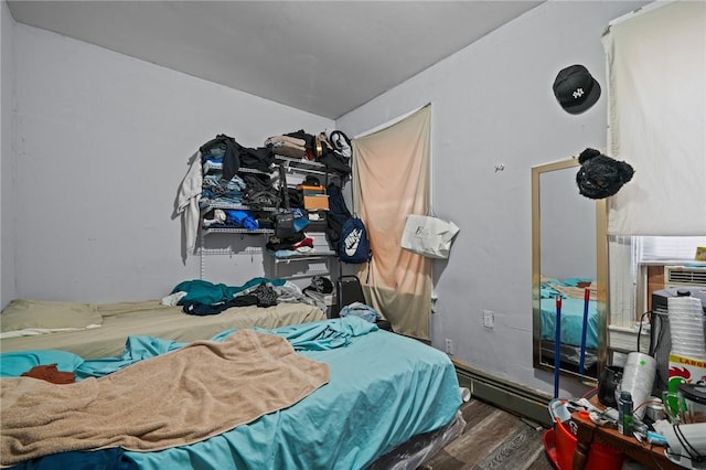 bedroom with a baseboard heating unit and wood finished floors