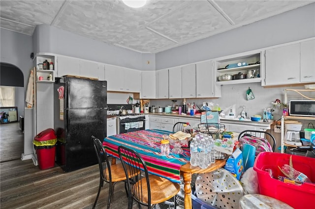 kitchen featuring range with gas stovetop, dark wood finished floors, freestanding refrigerator, white cabinetry, and open shelves