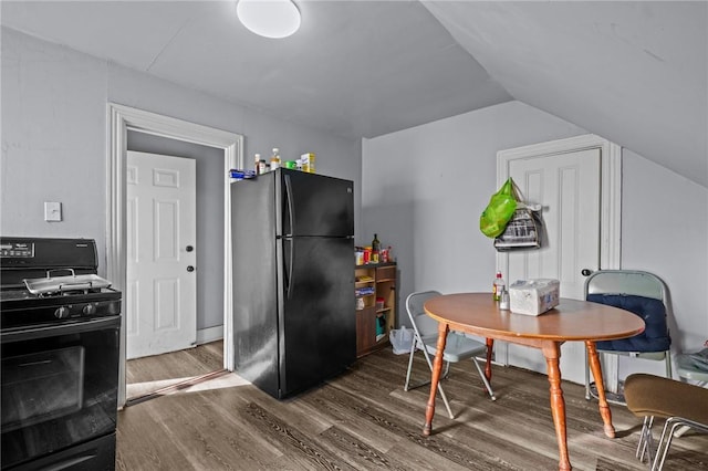 kitchen with dark wood-style floors, black appliances, and vaulted ceiling