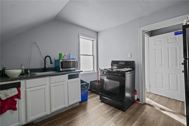 kitchen featuring dark wood-style flooring, stainless steel microwave, black gas range oven, white cabinets, and a sink