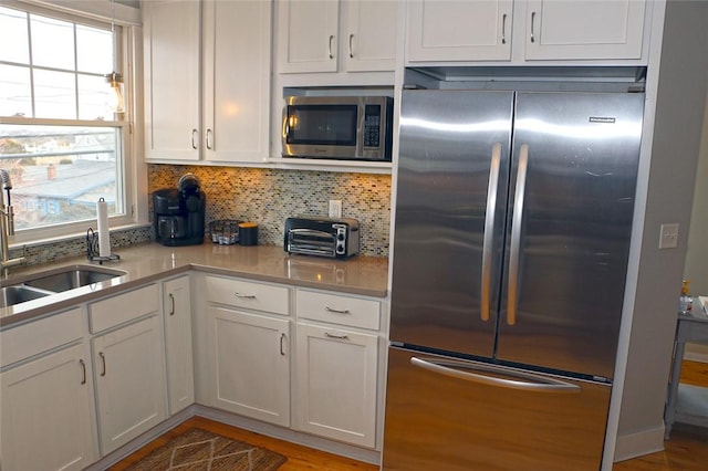 kitchen featuring tasteful backsplash, appliances with stainless steel finishes, a sink, and white cabinets