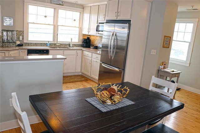 kitchen with stainless steel appliances, tasteful backsplash, a sink, and a healthy amount of sunlight