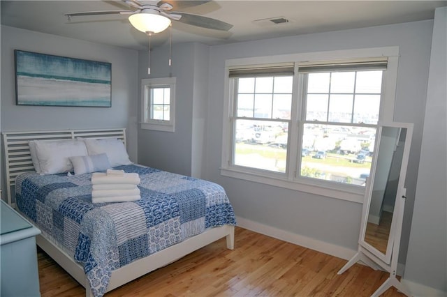 bedroom with visible vents, ceiling fan, baseboards, and wood finished floors