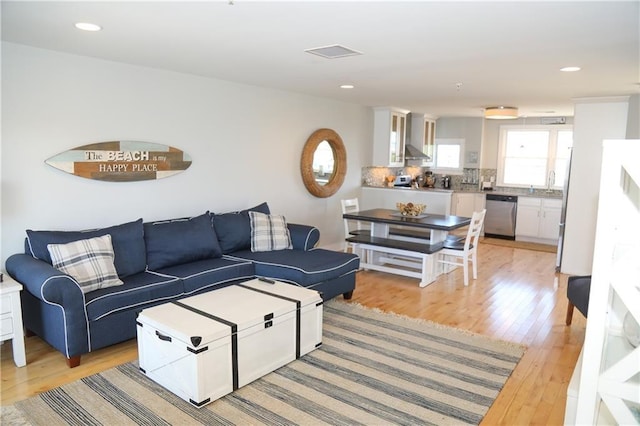 living room with light wood-type flooring, visible vents, and recessed lighting