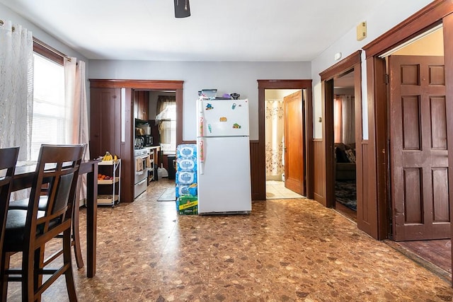 kitchen featuring a wainscoted wall, gas range, and freestanding refrigerator