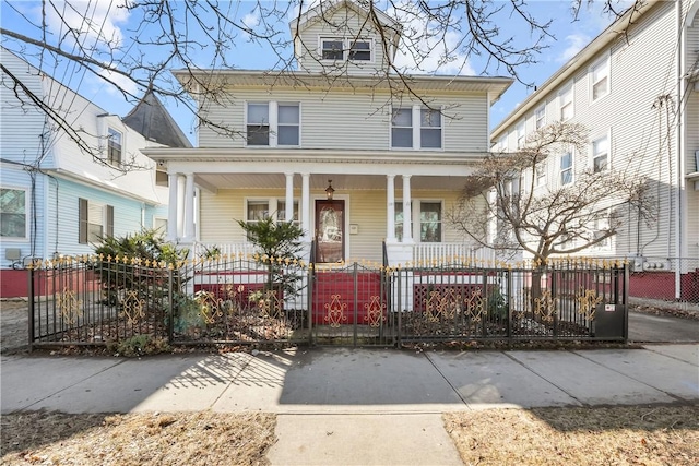 american foursquare style home with a porch and a fenced front yard