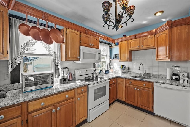 kitchen with white appliances, brown cabinetry, a sink, and light tile patterned flooring