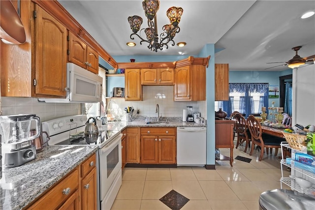 kitchen featuring white appliances, brown cabinetry, light tile patterned flooring, and a sink