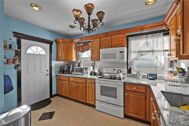 kitchen with white appliances, brown cabinets, decorative backsplash, and light stone countertops