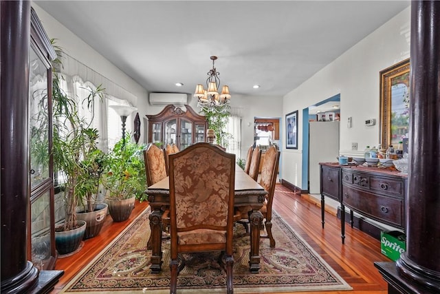 dining space featuring a wall unit AC, a chandelier, and wood finished floors