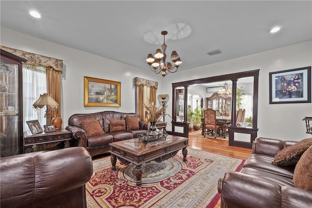 living area featuring a chandelier, recessed lighting, visible vents, light wood finished floors, and decorative columns