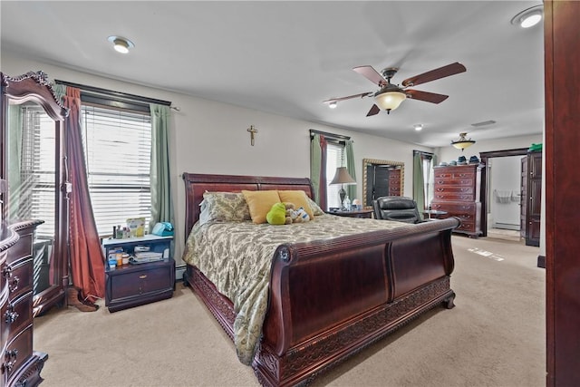 bedroom featuring multiple windows, a ceiling fan, and light colored carpet