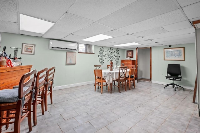 dining area with a paneled ceiling, baseboards, and a wall mounted AC