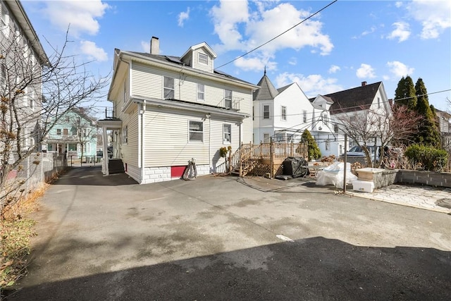 rear view of house with a chimney, fence, and a deck