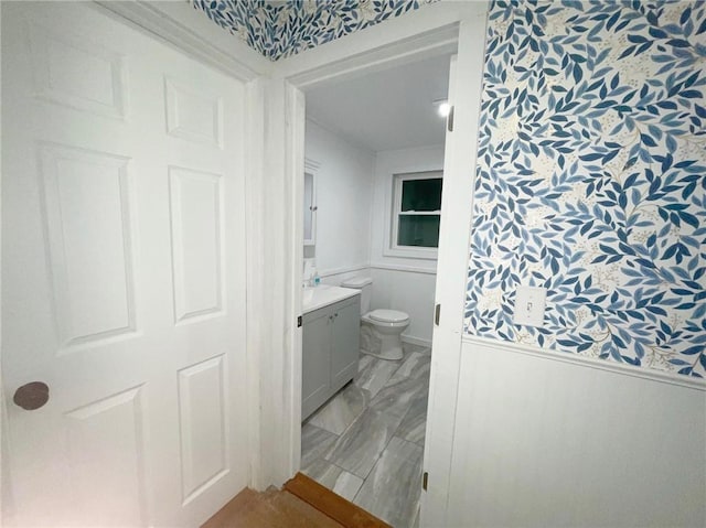 bathroom with vanity, toilet, and marble finish floor