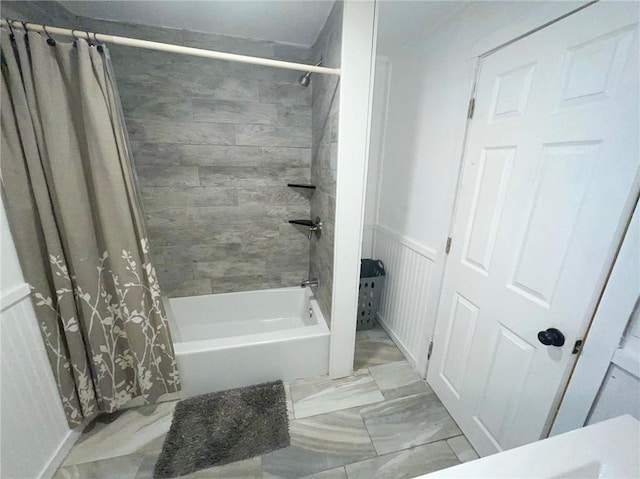 bathroom with a wainscoted wall and shower / tub combo with curtain