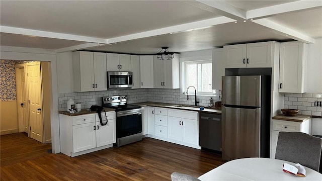 kitchen featuring dark wood-type flooring, dark countertops, appliances with stainless steel finishes, and a sink