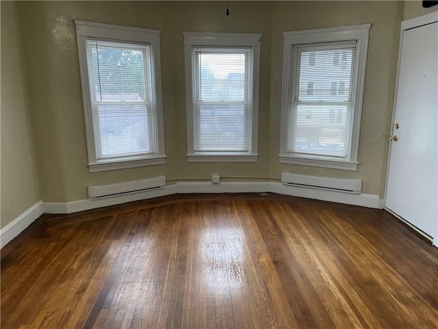 unfurnished room featuring a baseboard heating unit, hardwood / wood-style flooring, and baseboards