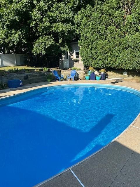 outdoor pool with fence and a diving board