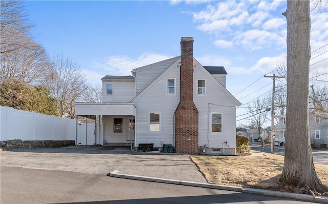 view of front of home with a chimney and fence