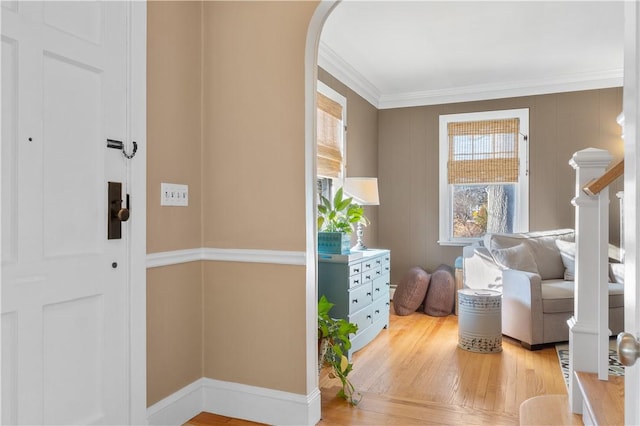 interior space featuring ornamental molding, light wood-type flooring, and arched walkways