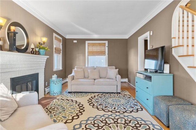 living room with a brick fireplace, stairs, ornamental molding, and wood finished floors