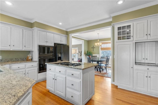 kitchen featuring black appliances, ornamental molding, white cabinets, and light wood-style floors