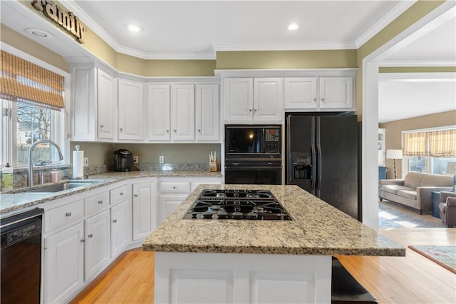 kitchen featuring a center island, white cabinets, a sink, and black appliances