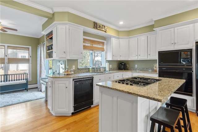 kitchen featuring white cabinetry, a sink, light wood finished floors, and black appliances