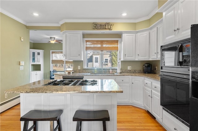 kitchen with a breakfast bar, a sink, light wood-style flooring, and a center island