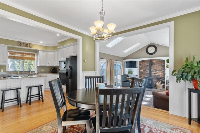 dining space with light wood-type flooring, a wood stove, and crown molding