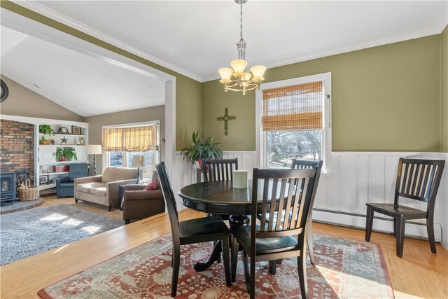 dining room with a wood stove, a healthy amount of sunlight, and wainscoting