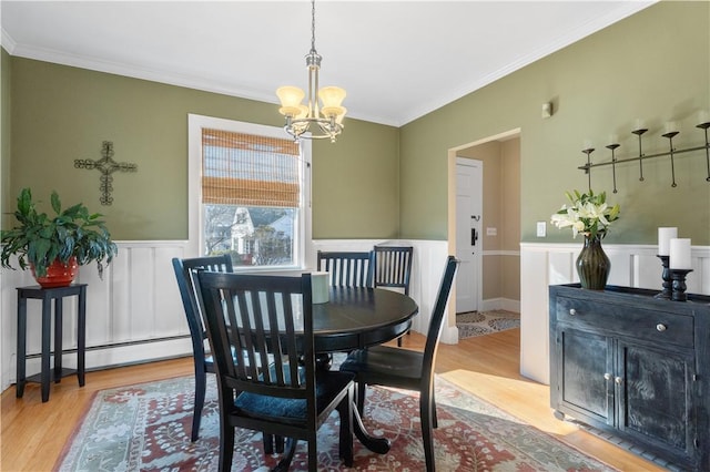 dining room with a wainscoted wall, crown molding, an inviting chandelier, and wood finished floors