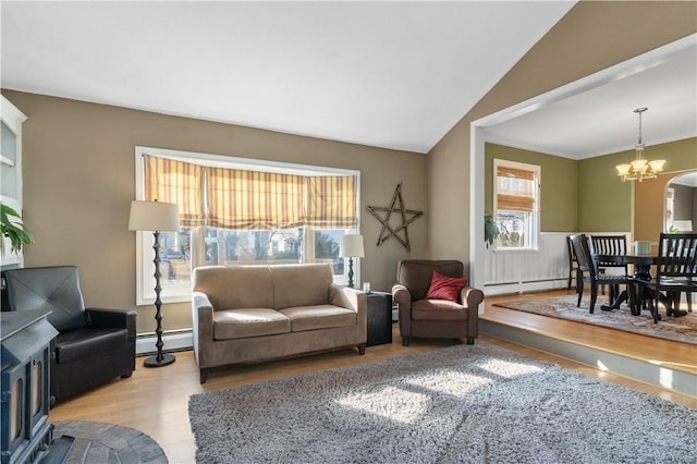 living room with a chandelier, lofted ceiling, wood finished floors, baseboard heating, and a baseboard heating unit