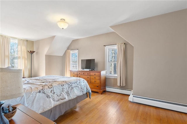 bedroom with vaulted ceiling, light wood-style flooring, and baseboard heating