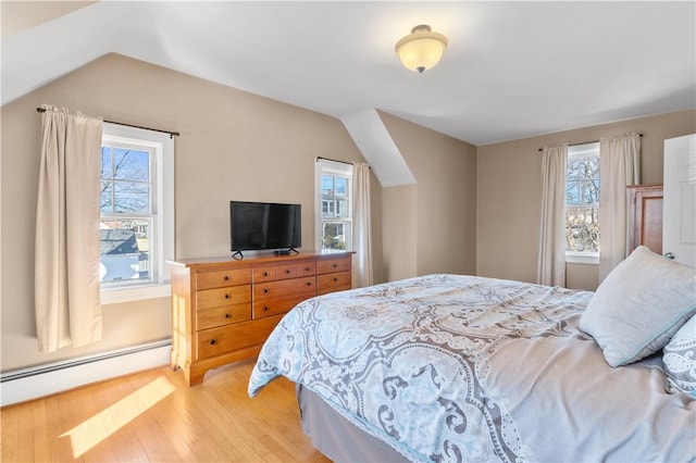 bedroom with lofted ceiling, light wood-style floors, and baseboard heating