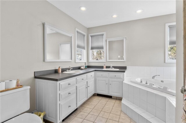 bathroom with double vanity, a garden tub, tile patterned flooring, and a sink