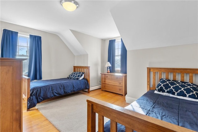 bedroom with a baseboard heating unit, multiple windows, and wood finished floors