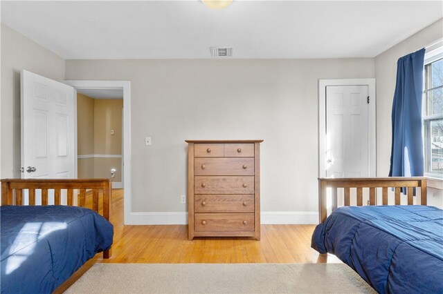 bedroom with visible vents, baseboards, and wood finished floors