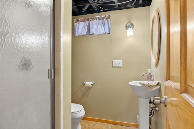 bathroom featuring toilet, a shower stall, baseboards, and tile patterned floors