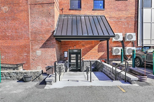 entrance to property with ac unit, a standing seam roof, brick siding, and metal roof