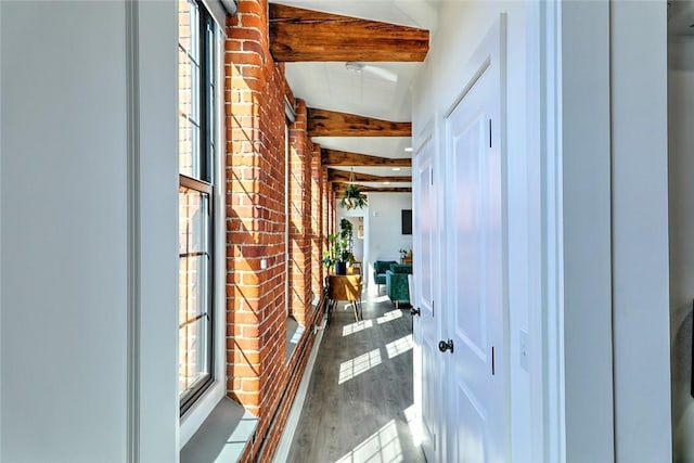 corridor featuring brick wall, beam ceiling, and wood finished floors