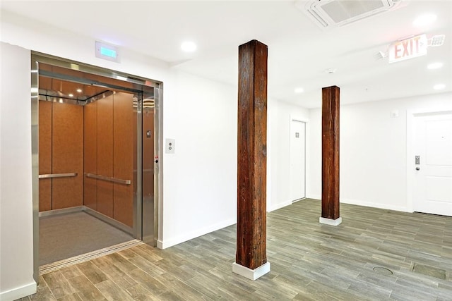 interior space featuring recessed lighting, wood finished floors, visible vents, baseboards, and elevator