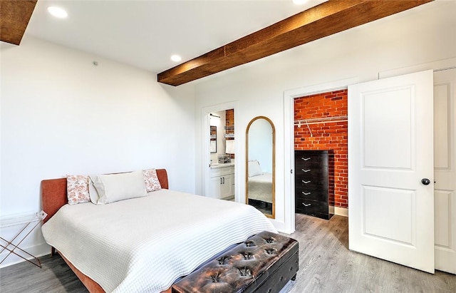 bedroom with light wood finished floors, a walk in closet, beamed ceiling, and recessed lighting