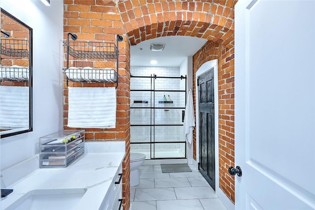 kitchen featuring light stone counters, marble finish floor, and brick wall