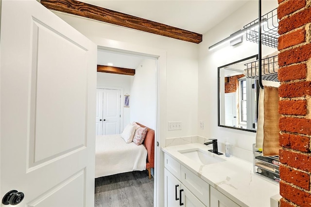 bathroom featuring beamed ceiling, vanity, and wood finished floors