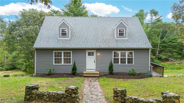 cape cod-style house featuring roof with shingles and a front lawn