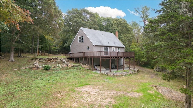 exterior space featuring a yard, a chimney, a wooden deck, and a patio