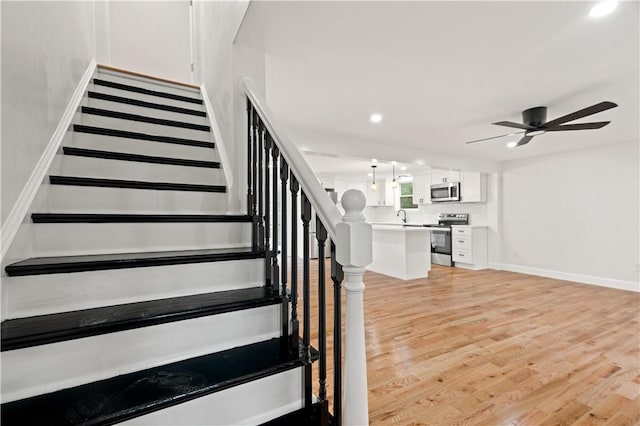 staircase with a ceiling fan, baseboards, wood finished floors, and recessed lighting