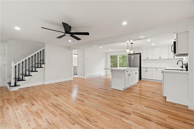 kitchen featuring a baseboard radiator, light wood-style flooring, a center island, freestanding refrigerator, and a sink